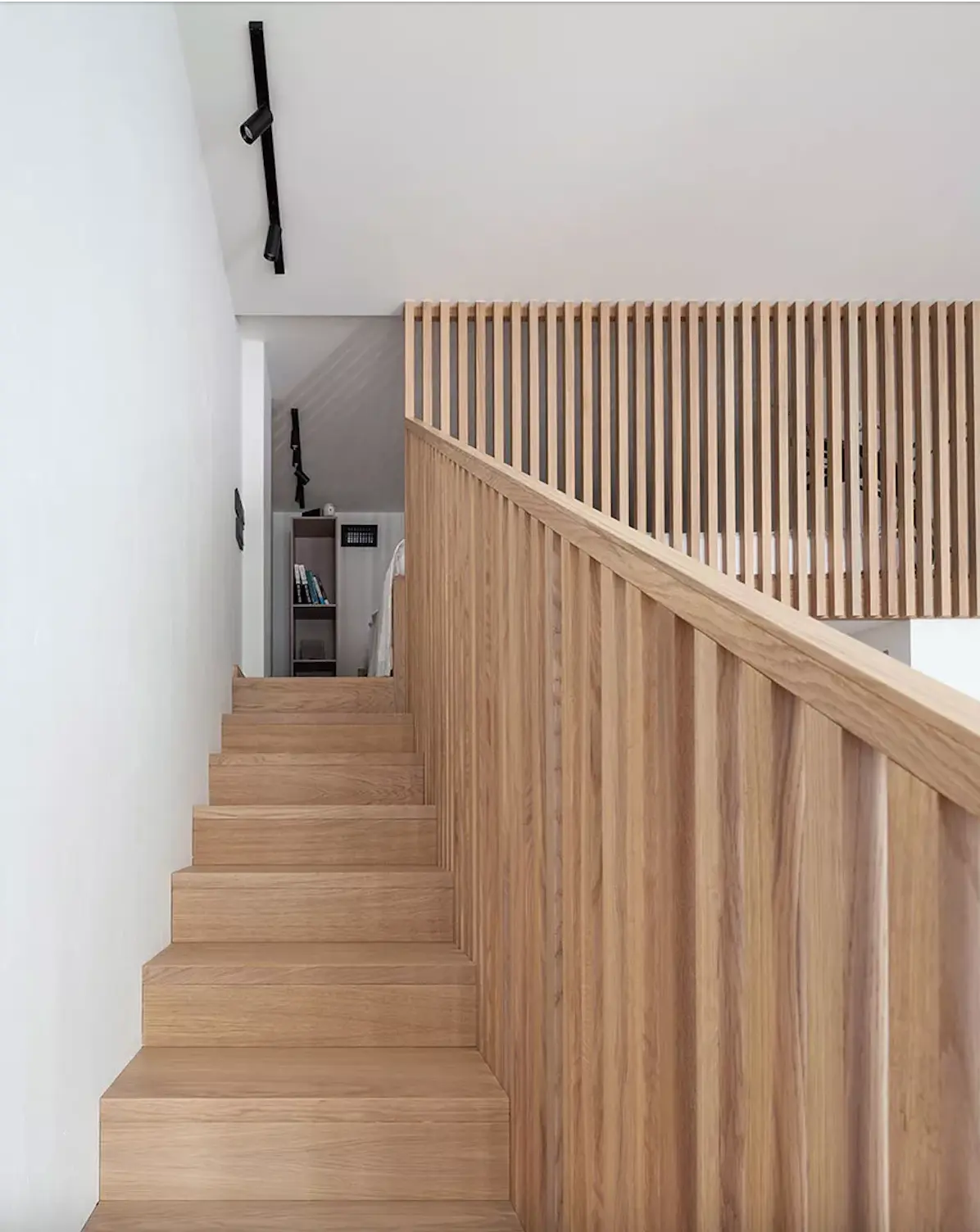 Escalera de madera con diseño minimalista y barandilla de listones.
