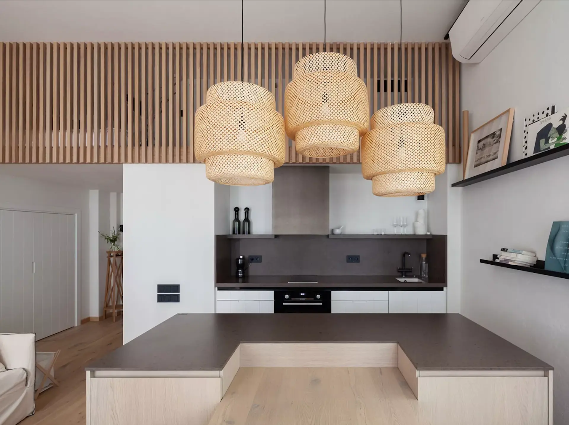 Cocina moderna con lámparas de mimbre y barra en tonos madera.