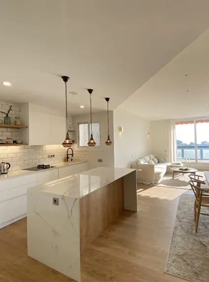 Cocina abierta de estilo moderno con isla de mármol y salón comedor integrado.