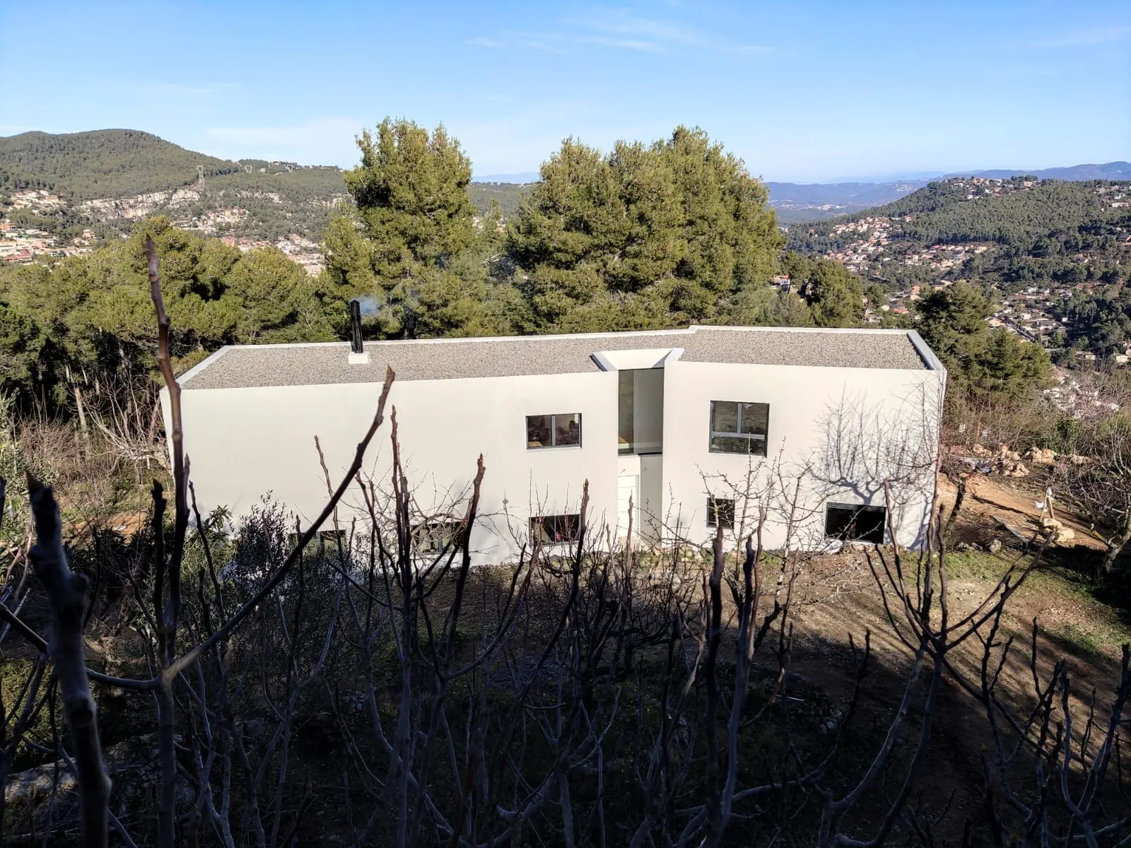 Proyecto de reforma de salón comedor en un estilo moderno y acogedor. El espacio incluye una mesa ovalada de madera natural rodeada de sillas grises y una lámpara colgante que aporta calidez al ambiente. La disposición abierta conecta el comedor con el área de estar, que cuenta con un sofá cómodo y estanterías integradas para almacenamiento. Este diseño optimiza el espacio y la funcionalidad, creando un ambiente perfecto para la convivencia diaria y el entretenimiento